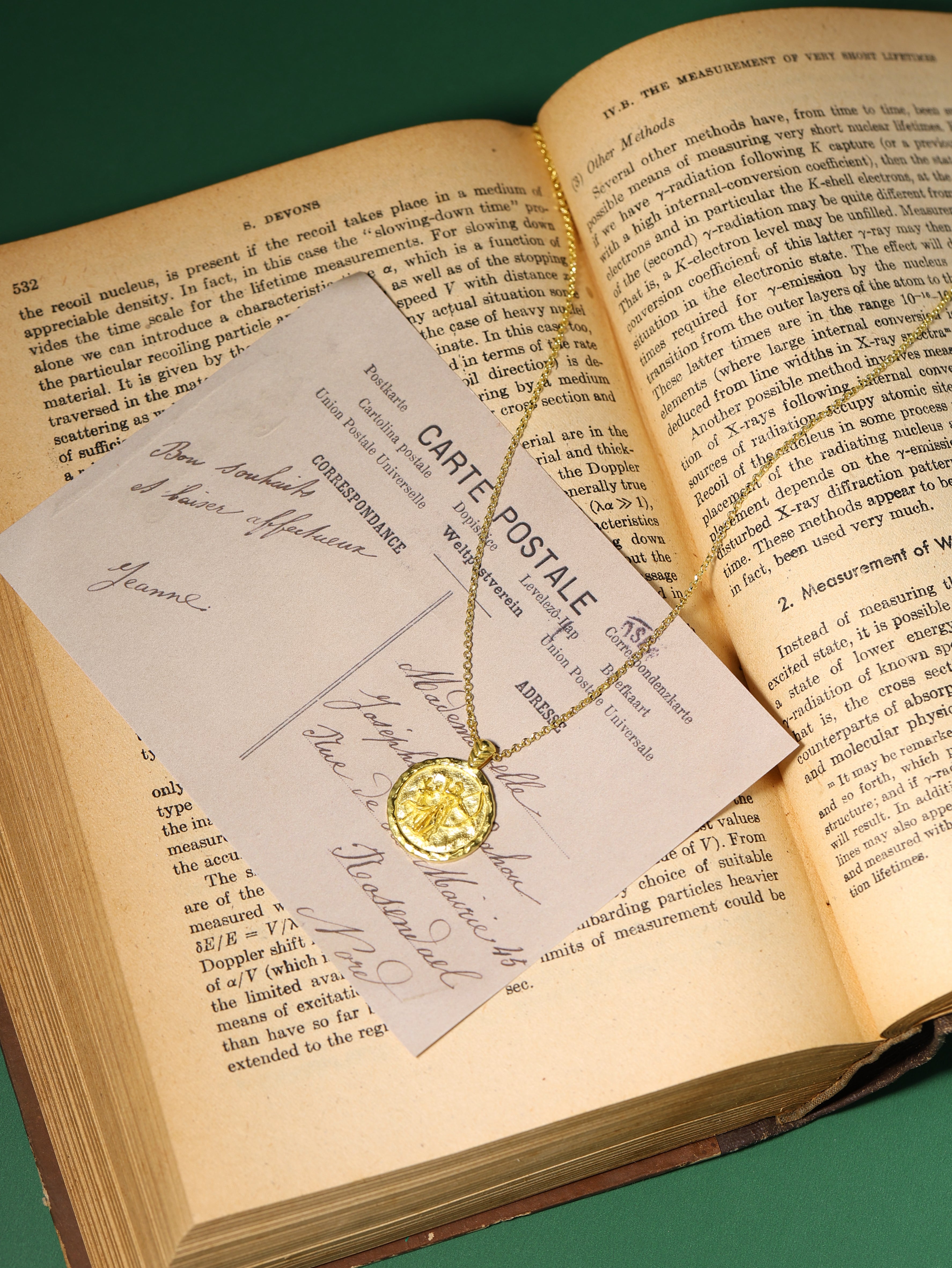 Gold necklace with a pendant on a card over an open book