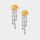 Gold rose-shaped earrings with diamond-like stones on a white background
