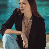 Woman sitting by a pool wearing a black blazer and light blue jeans.