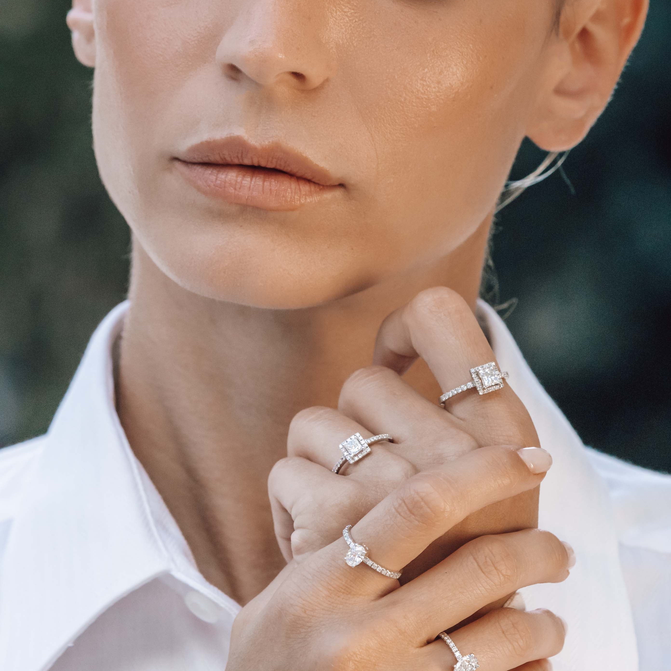 Close-up of a woman wearing multiple engagement diamond rings on her fingers.