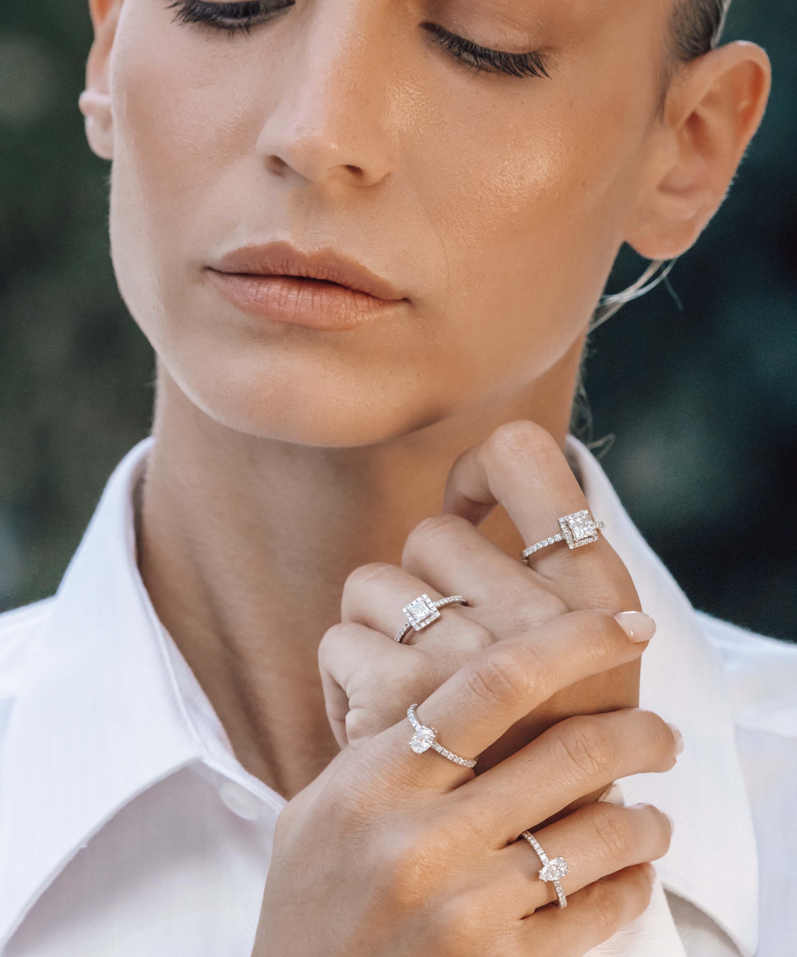 Close-up of a woman wearing multiple engagement diamond rings on her fingers.