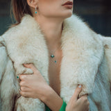 Close-up of a person wearing a fur coat and emerald jewellery with a blurred background