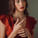 Woman wearing a red dress with jewelry against a neutral background