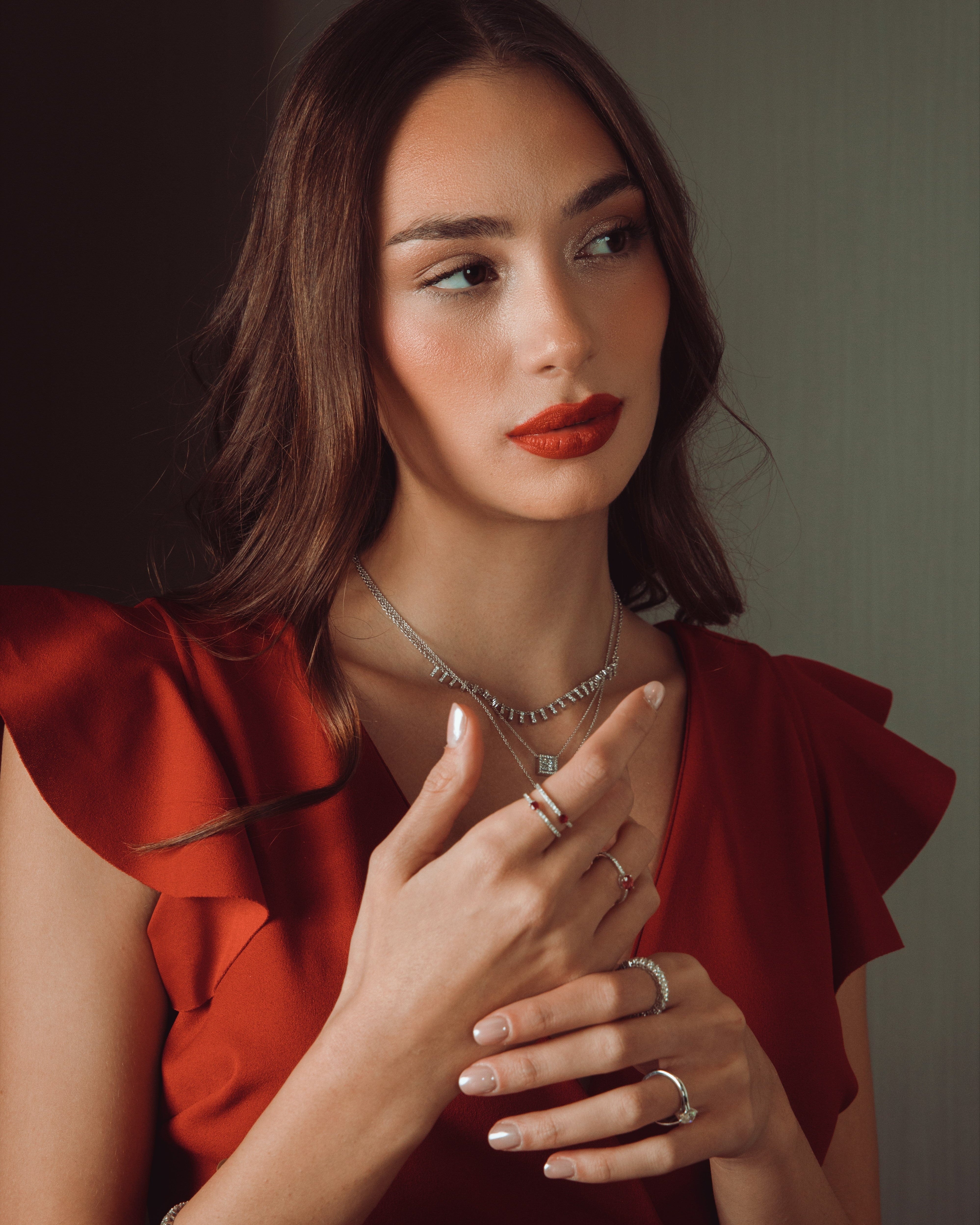 Woman wearing a red dress with jewelry against a neutral background