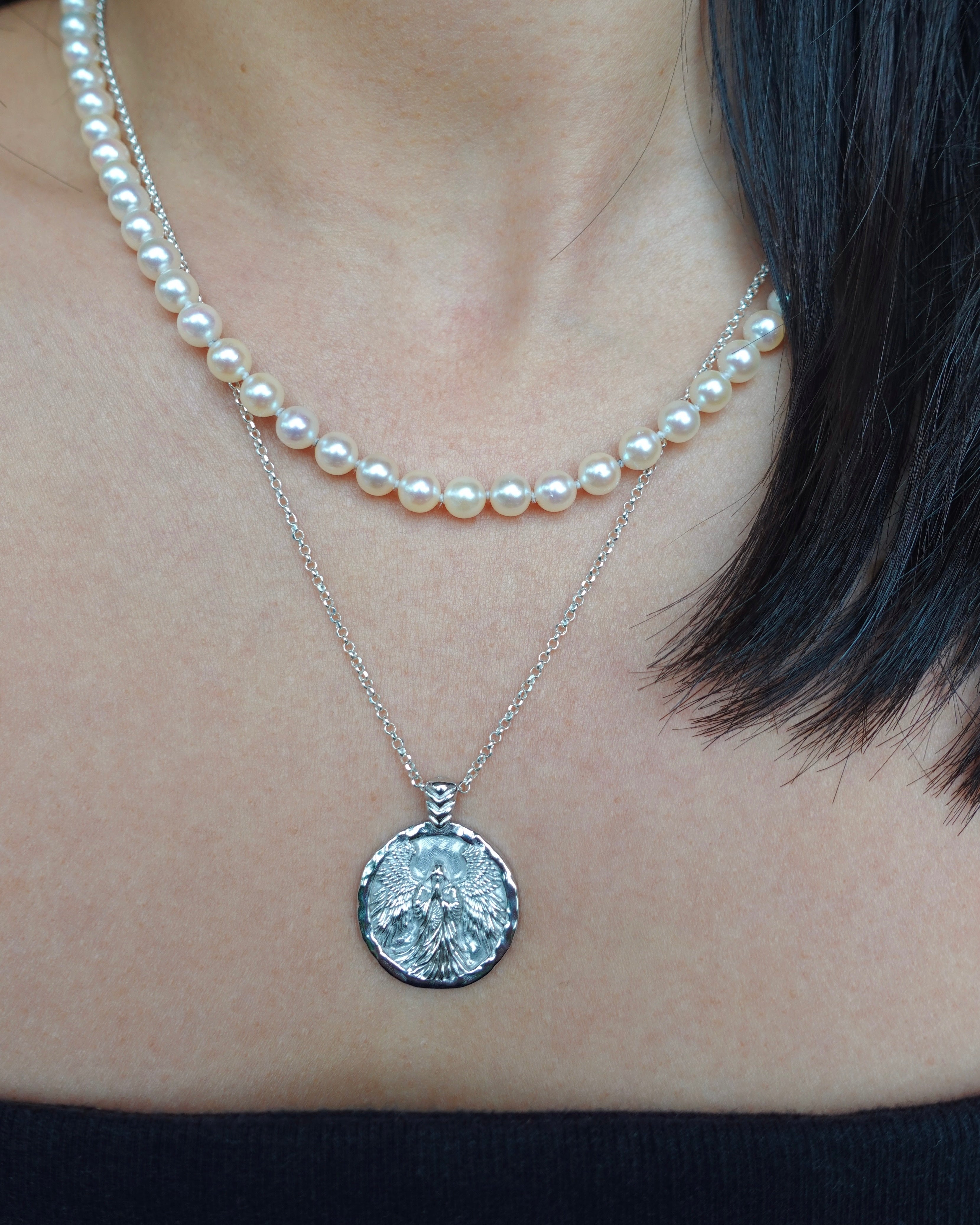 Pearl necklace with a silver pendant worn by a person