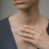 Woman wearing a gold necklace with a cross pendant, holding it close to her chest.