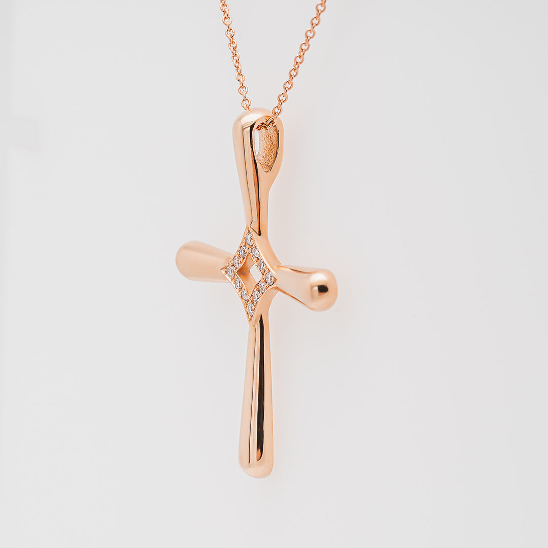 Rose gold cross pendant necklace on a light gray background