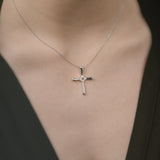 White gold cross necklace on a person wearing a black top