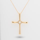 Gold cross necklace with diamonds on a light gray background