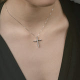 Close-up of a person wearing a gold necklace with a cross pendant.