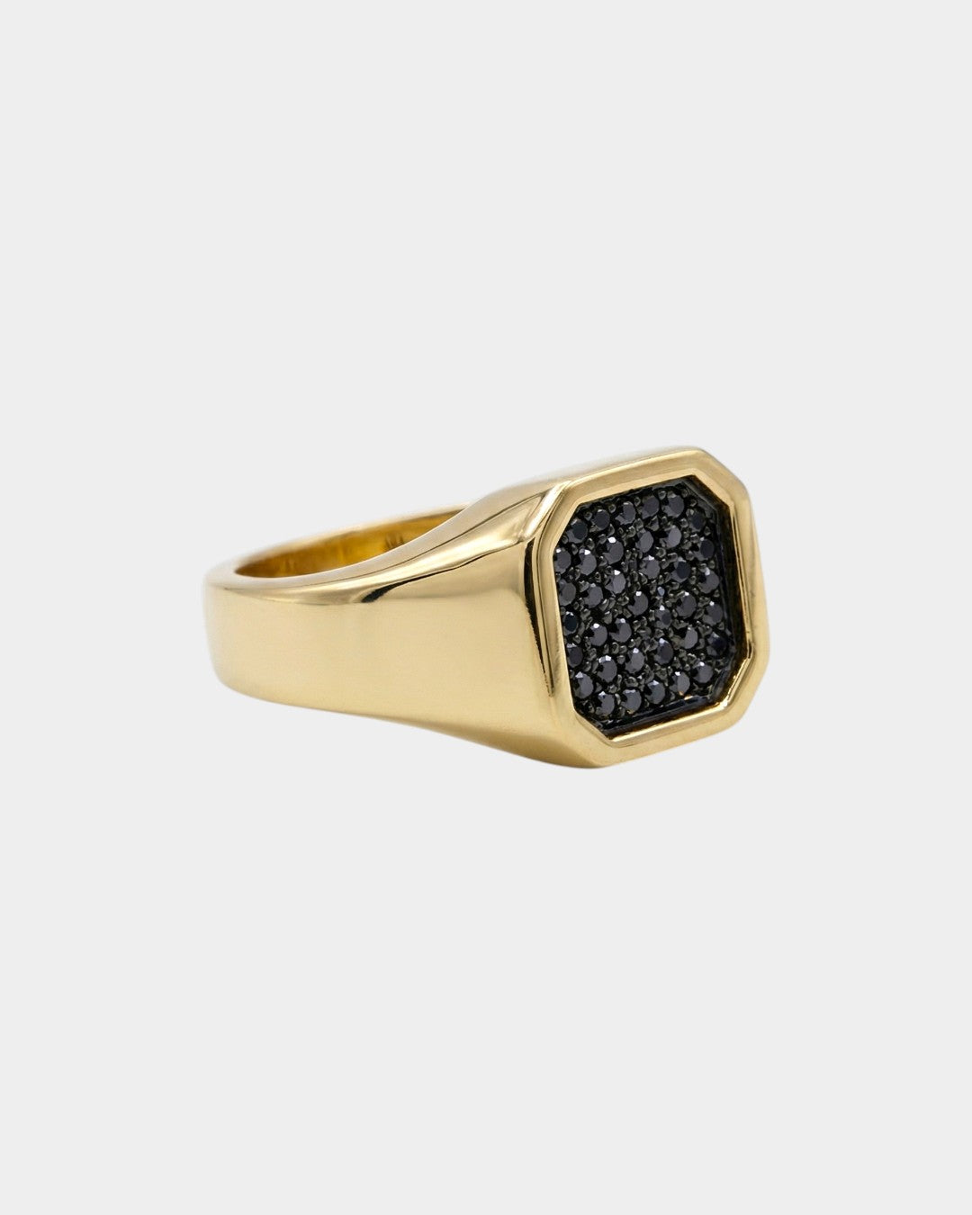 Gold ring with black diamonds on a light gray background