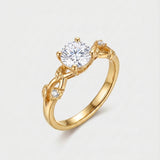 Gold ring with a diamond with a vine shape shank on a light gray background
