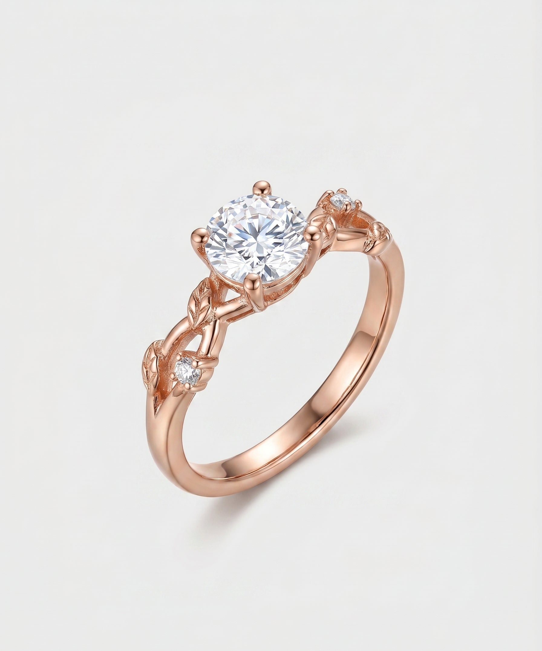 Rose gold ring with a diamond over a vine leaf on a light gray background