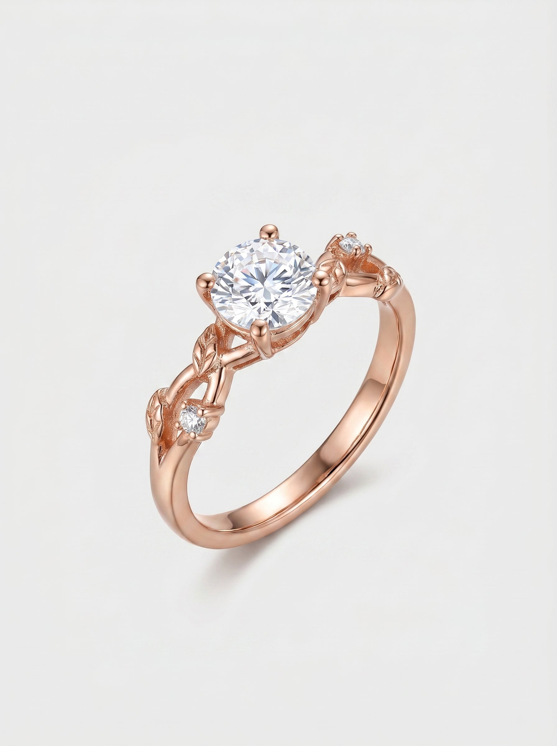 Rose gold ring with a diamond over a vine leaf on a light gray background