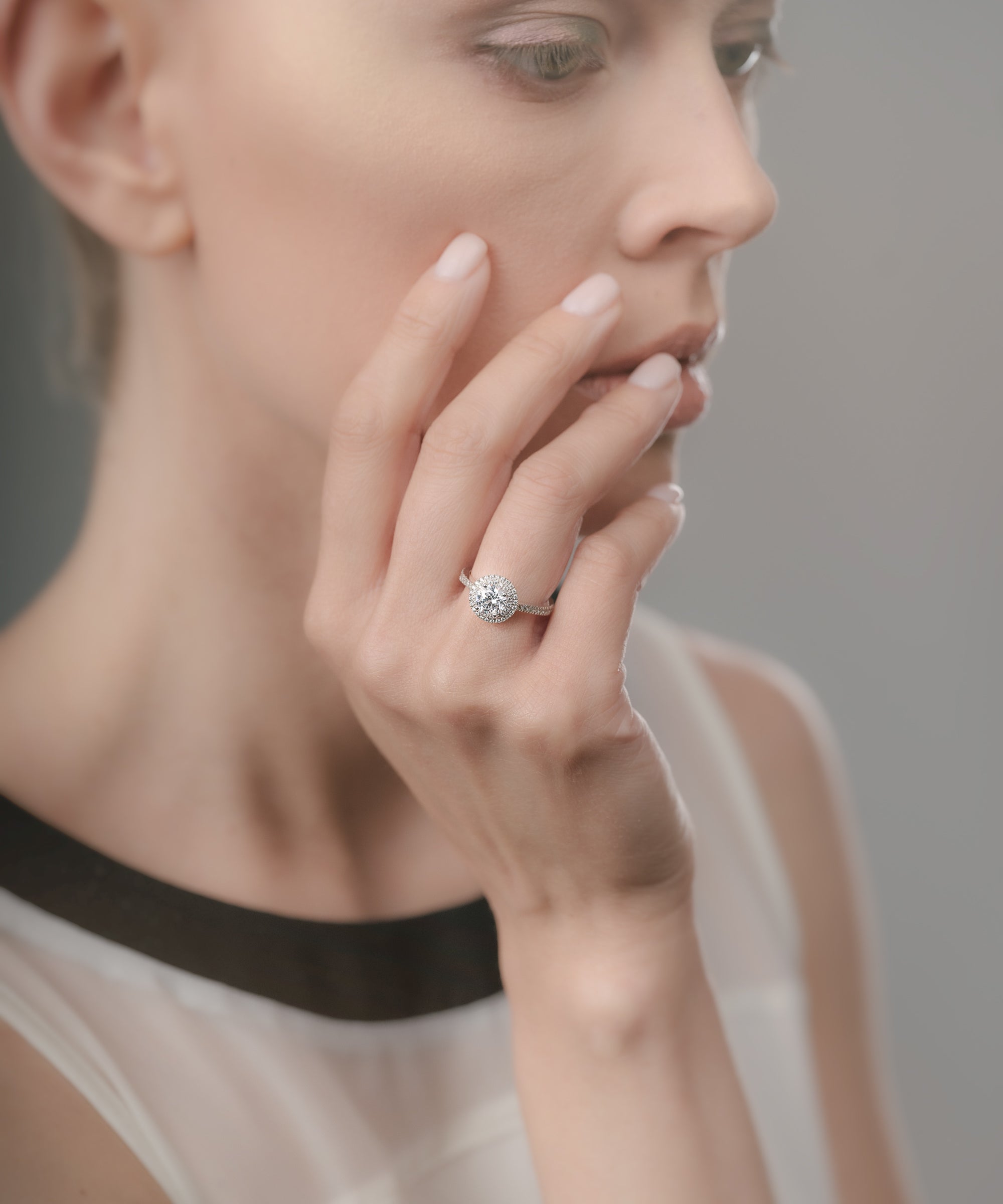 Woman wearing a diamond ring on her finger against a neutral background