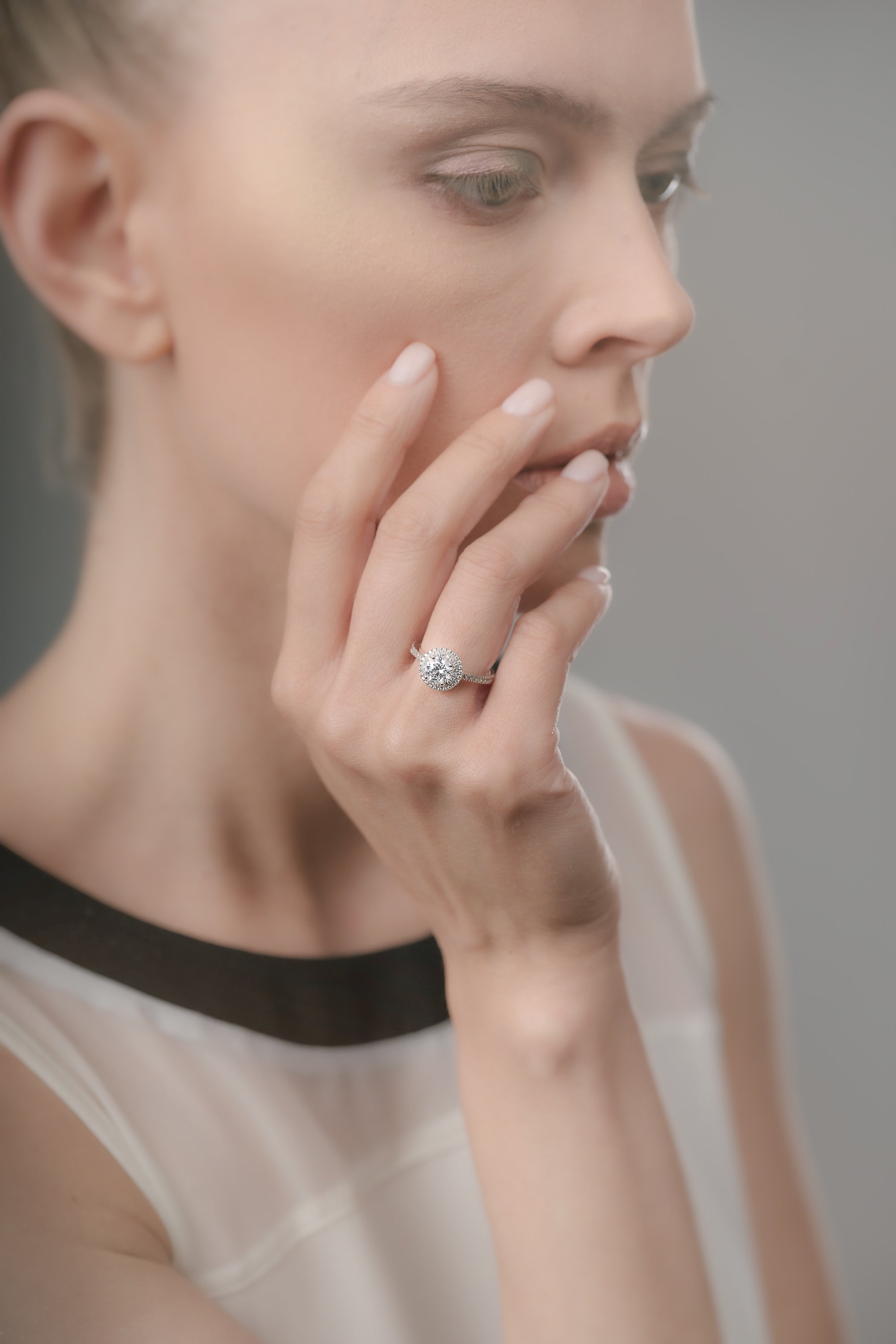 Woman wearing a diamond ring on her finger against a neutral background