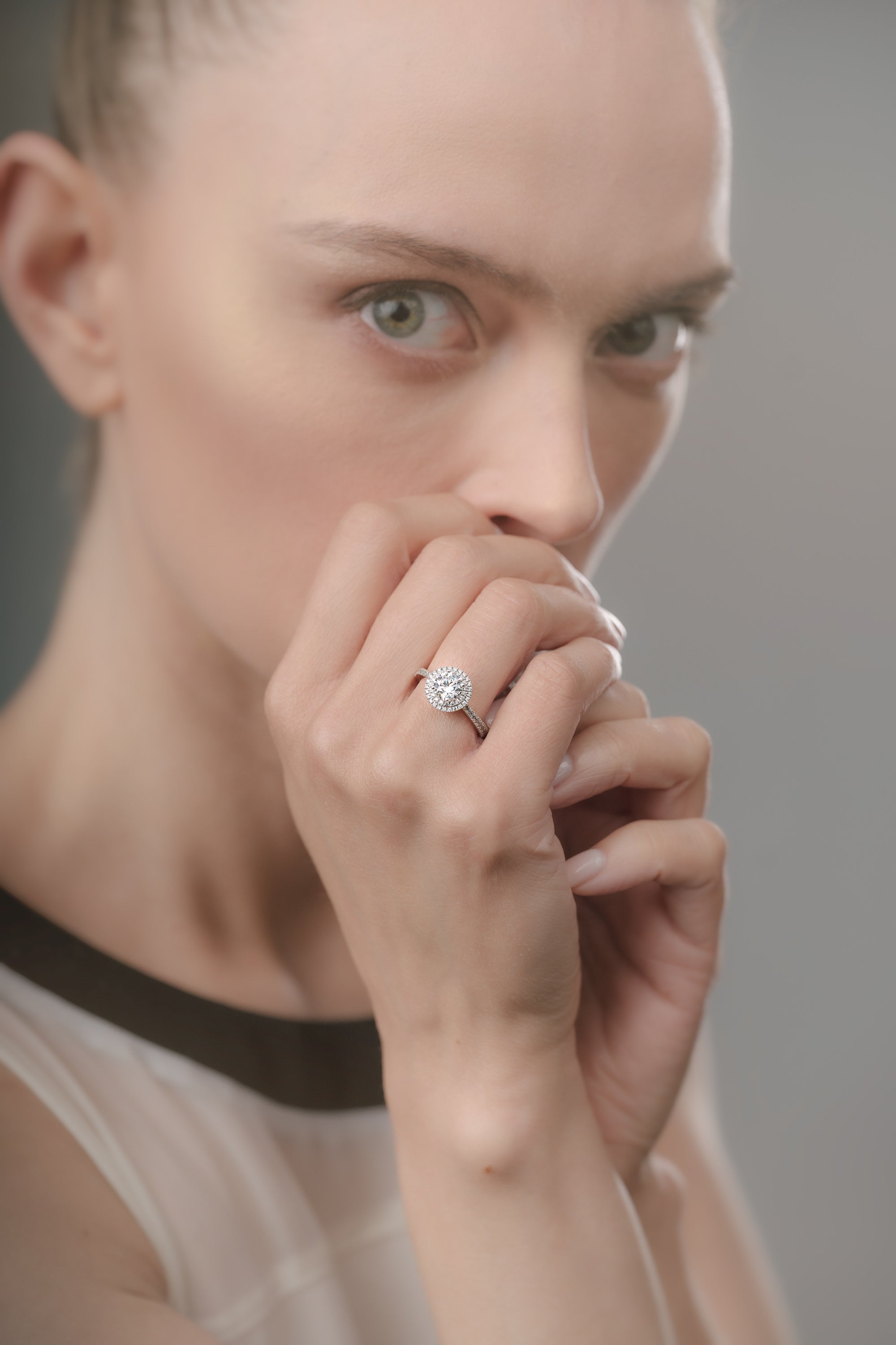 Woman wearing a diamond ring on her finger against a neutral background