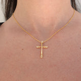Gold cross necklace with diamonds on a person's neck