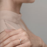 Close-up of a hand wearing an engagement ring with a blurred background