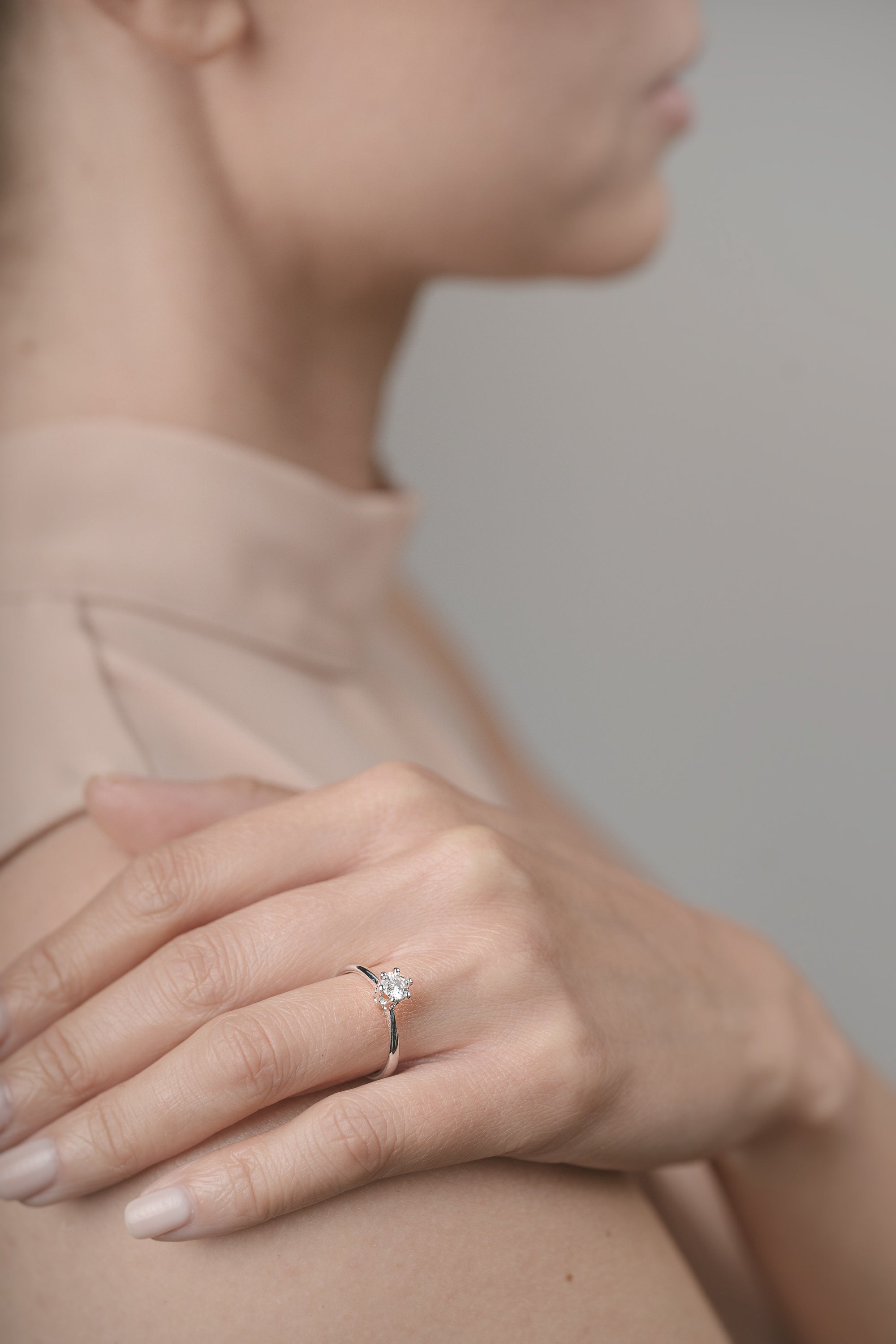 Close-up of a hand wearing an engagement ring with a blurred background