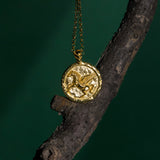 Gold necklace with a pendant hanging on a dark branch against a dark background