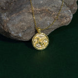 Gold necklace with a round pendant on a dark surface