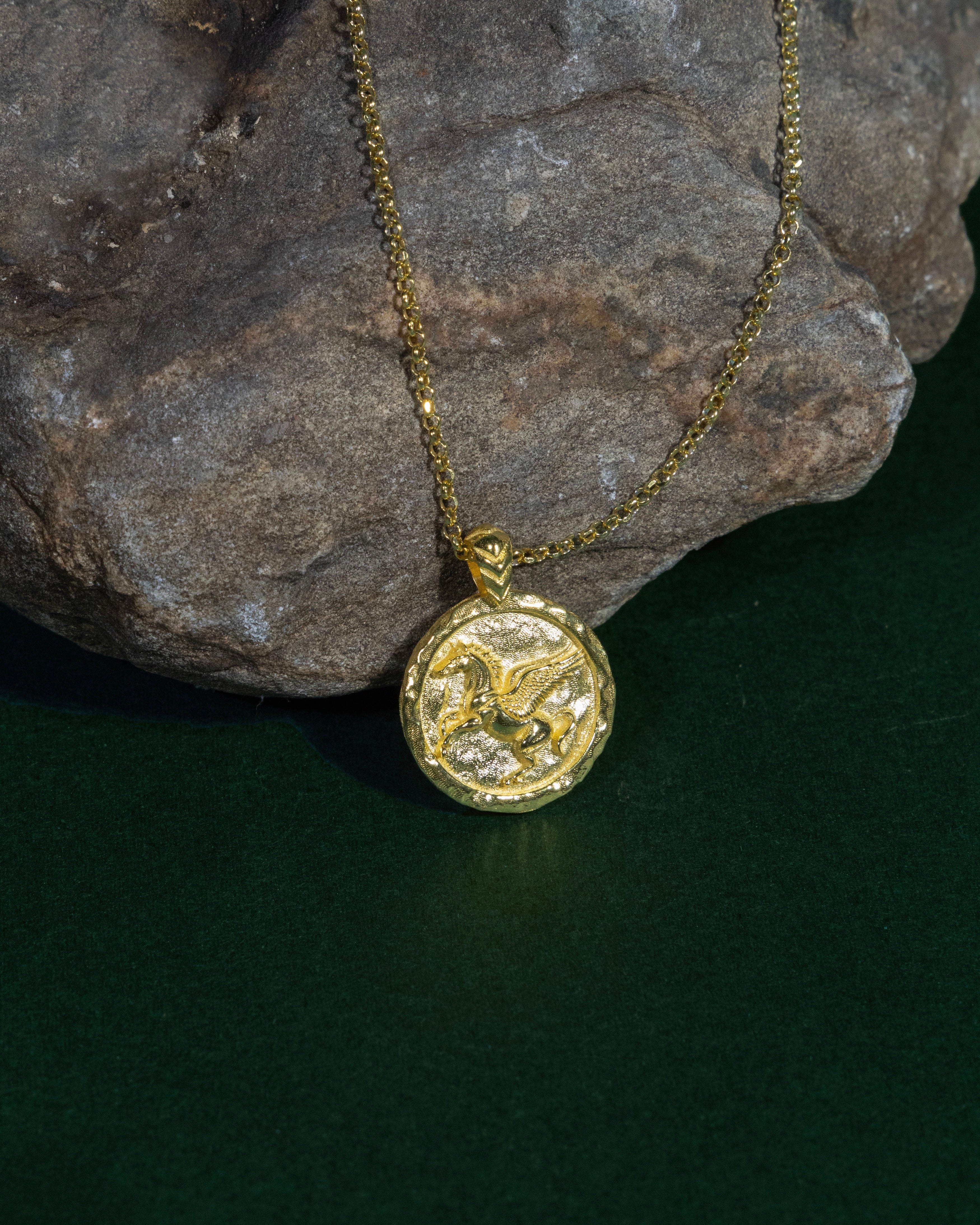 Gold necklace with a round pendant on a dark surface