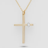 Gold cross pendant with a diamond on a light gray background