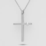 Silver cross pendant with a diamond on a light gray background