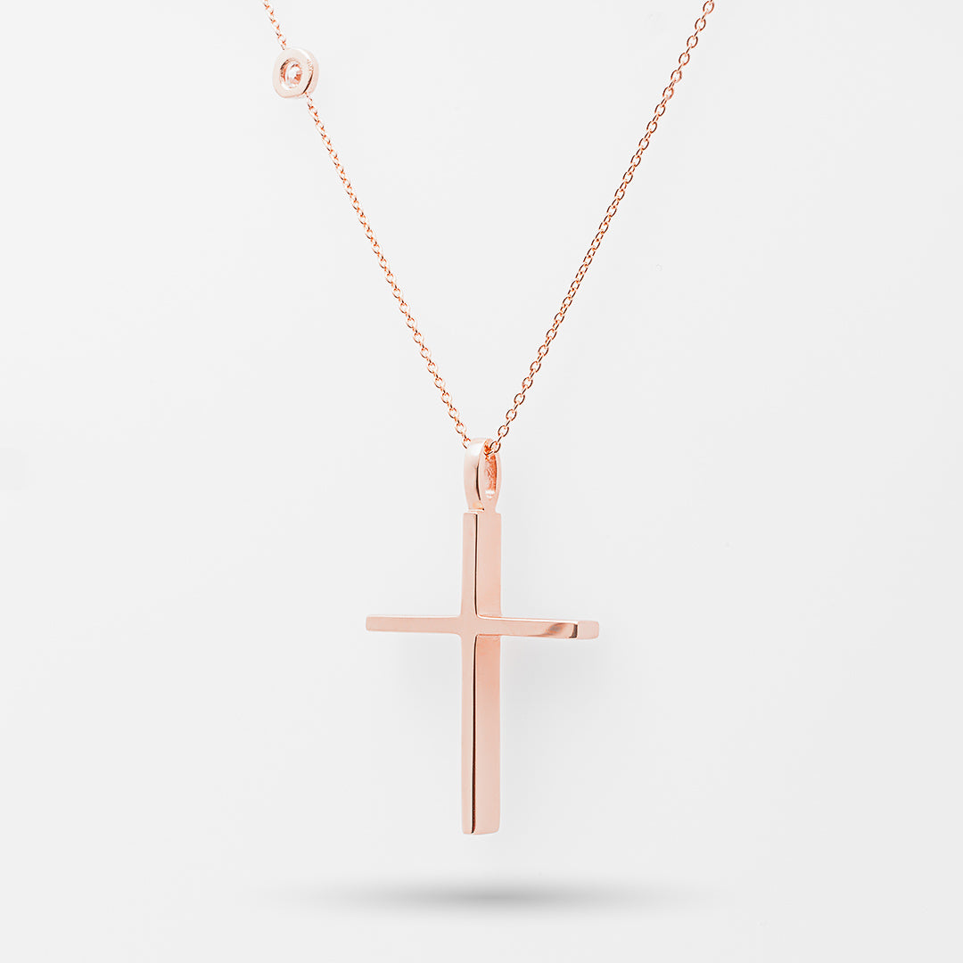 Rose gold cross necklace on a light gray background