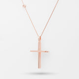 Rose gold cross necklace on a light gray background
