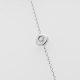 White gold necklace with a small round pendant on a light gray background