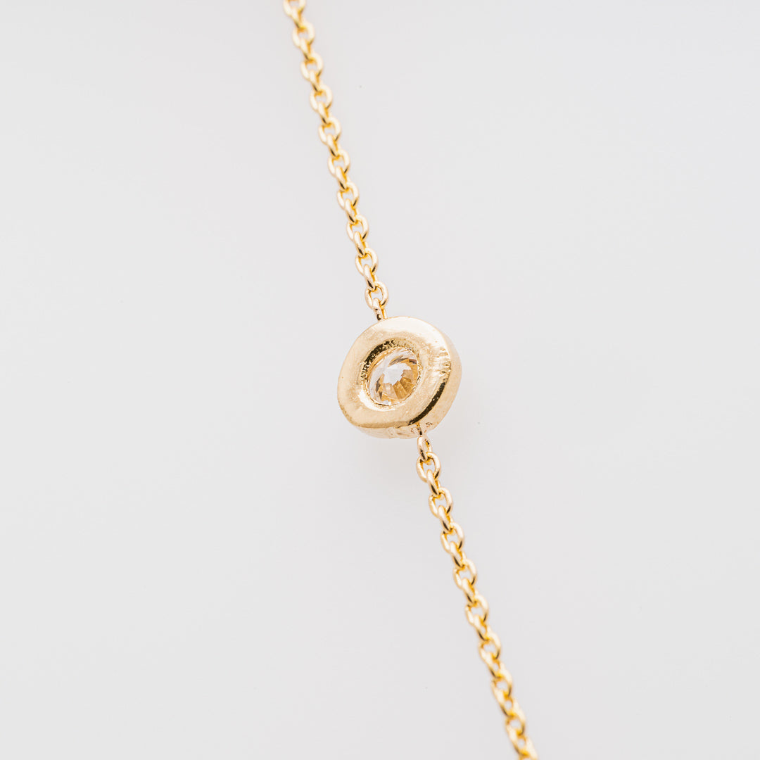 Gold necklace with a round pendant on a light gray background