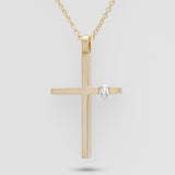 Gold cross pendant with a diamond on a light gray background