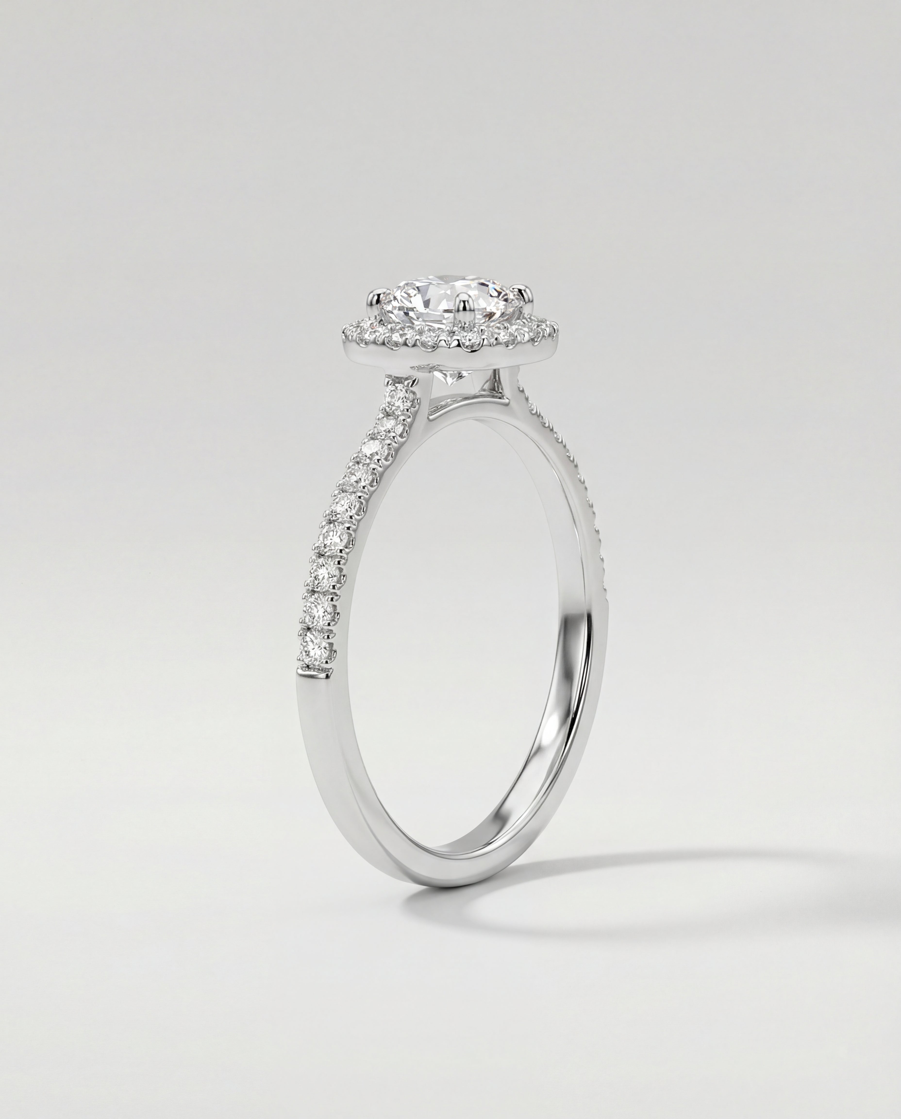 Diamond ring with a halo and side stones on a light gray background
