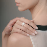Close-up of a woman wearing a white-gold diamond ring on her finger with a blurred background