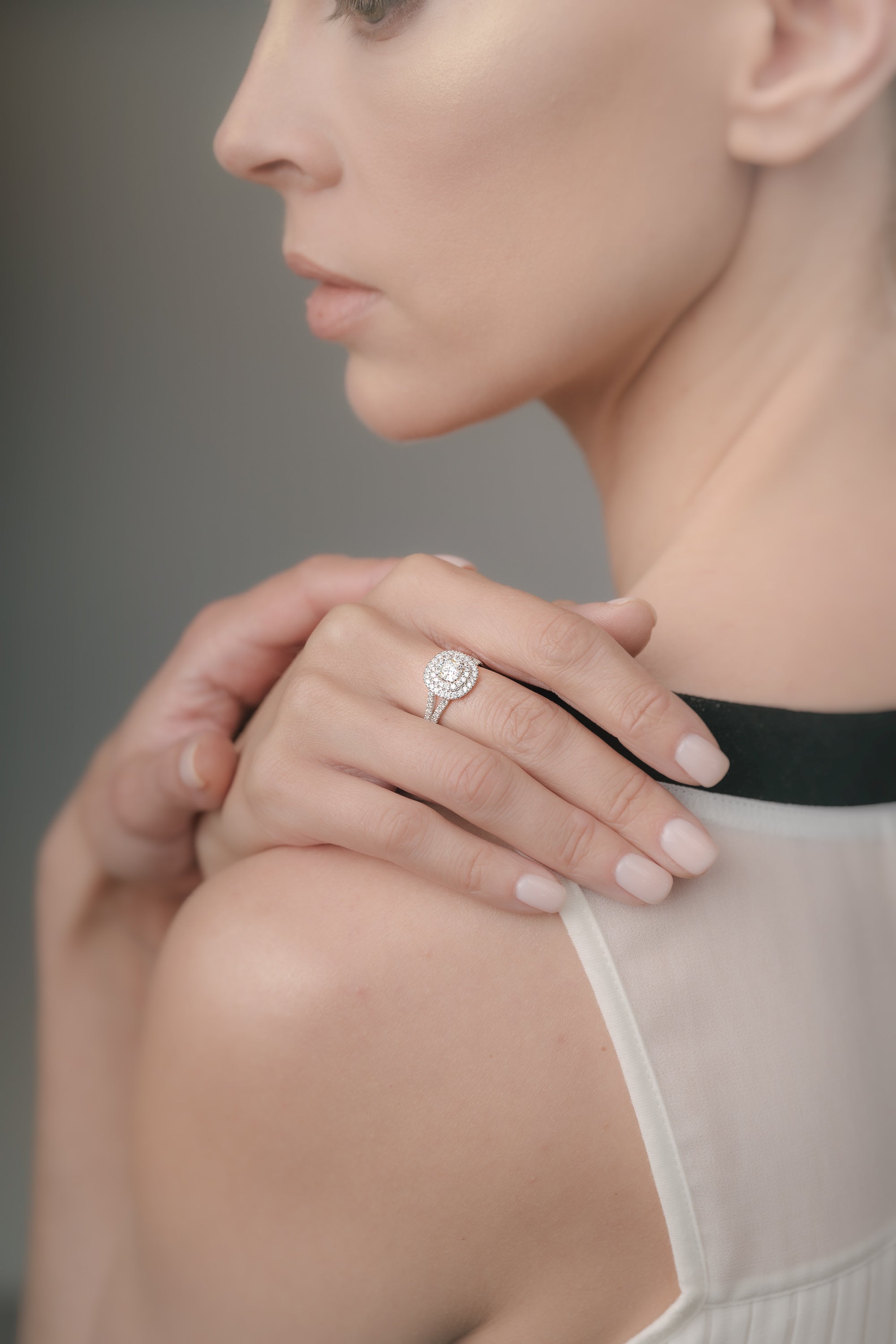 Close-up of a woman wearing a white-gold diamond ring on her finger with a blurred background