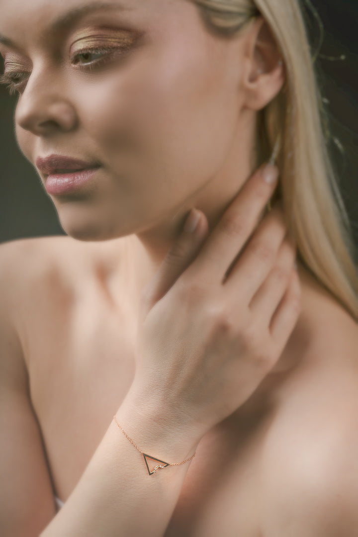 Woman wearing a gold triangle bracelet on her wrist