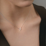 Person wearing a delicate white gold necklace with a triangle pendant.
