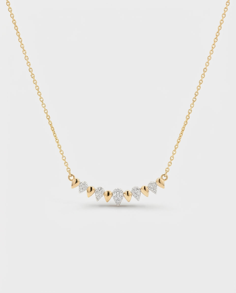 Gold necklace with diamond pendants on a light gray background