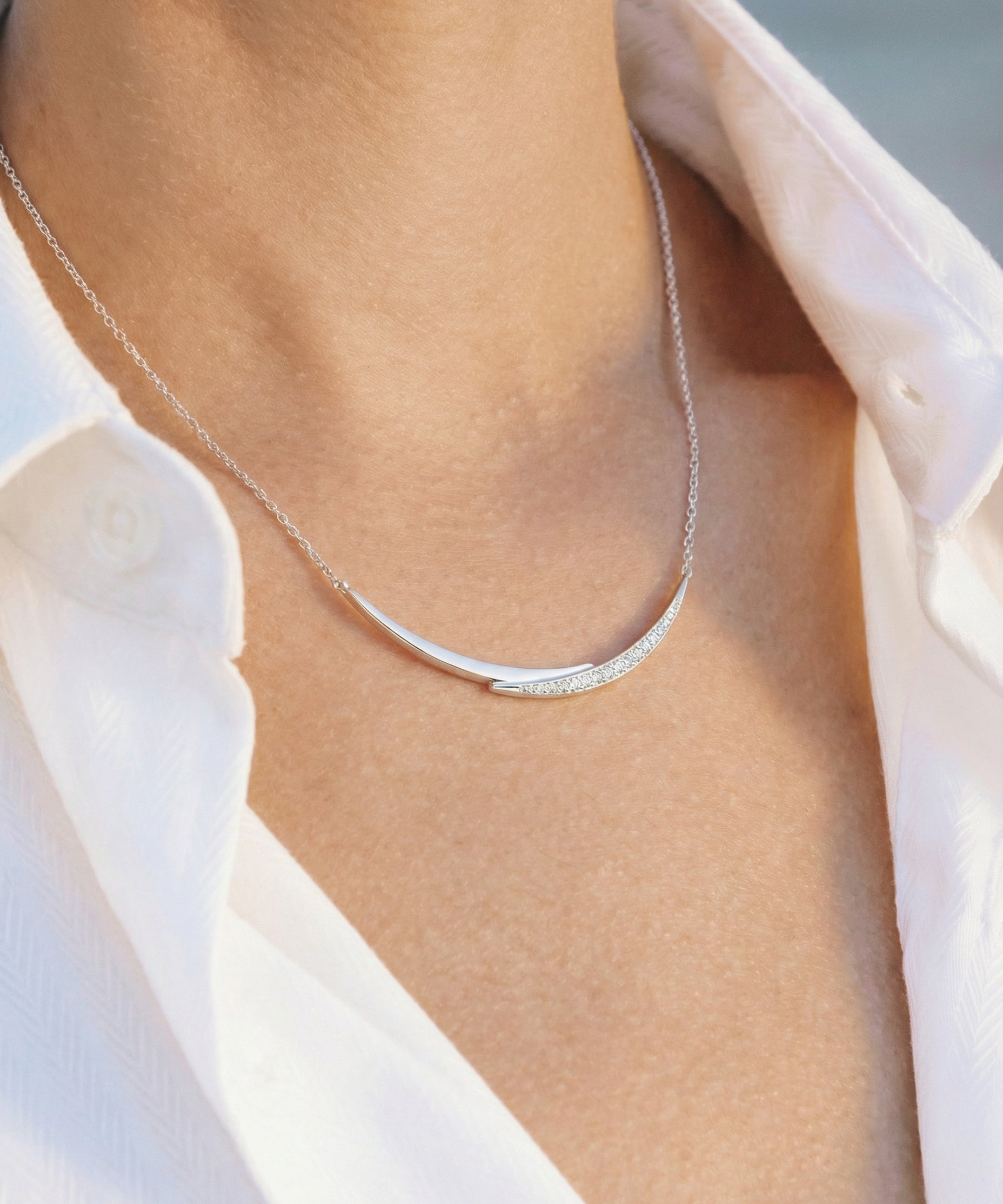 white gold with diamond smile necklace worn by a person with a white shirt