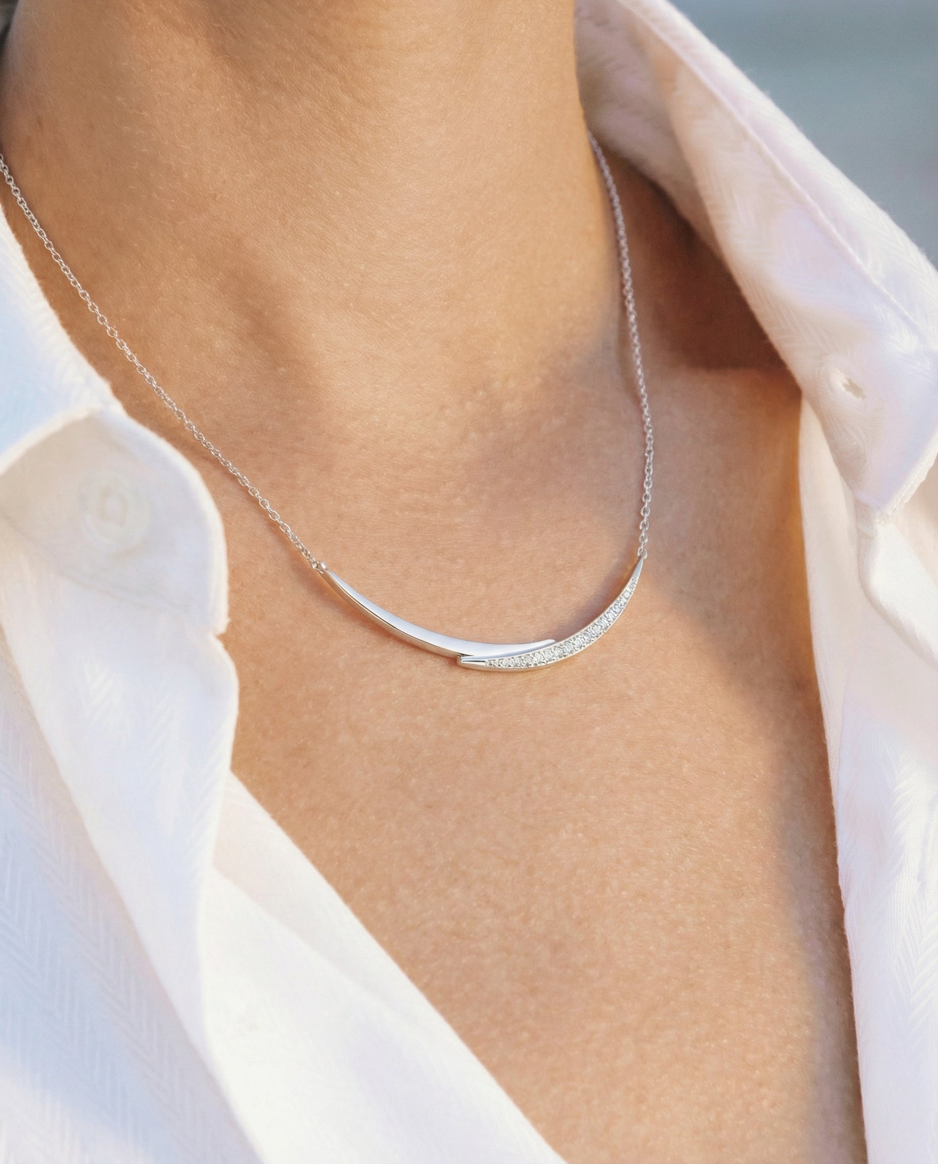 white gold with diamond smile necklace worn by a person with a white shirt