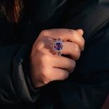 Close-up of a hand wearing a ring with a blue gemstone against a dark background