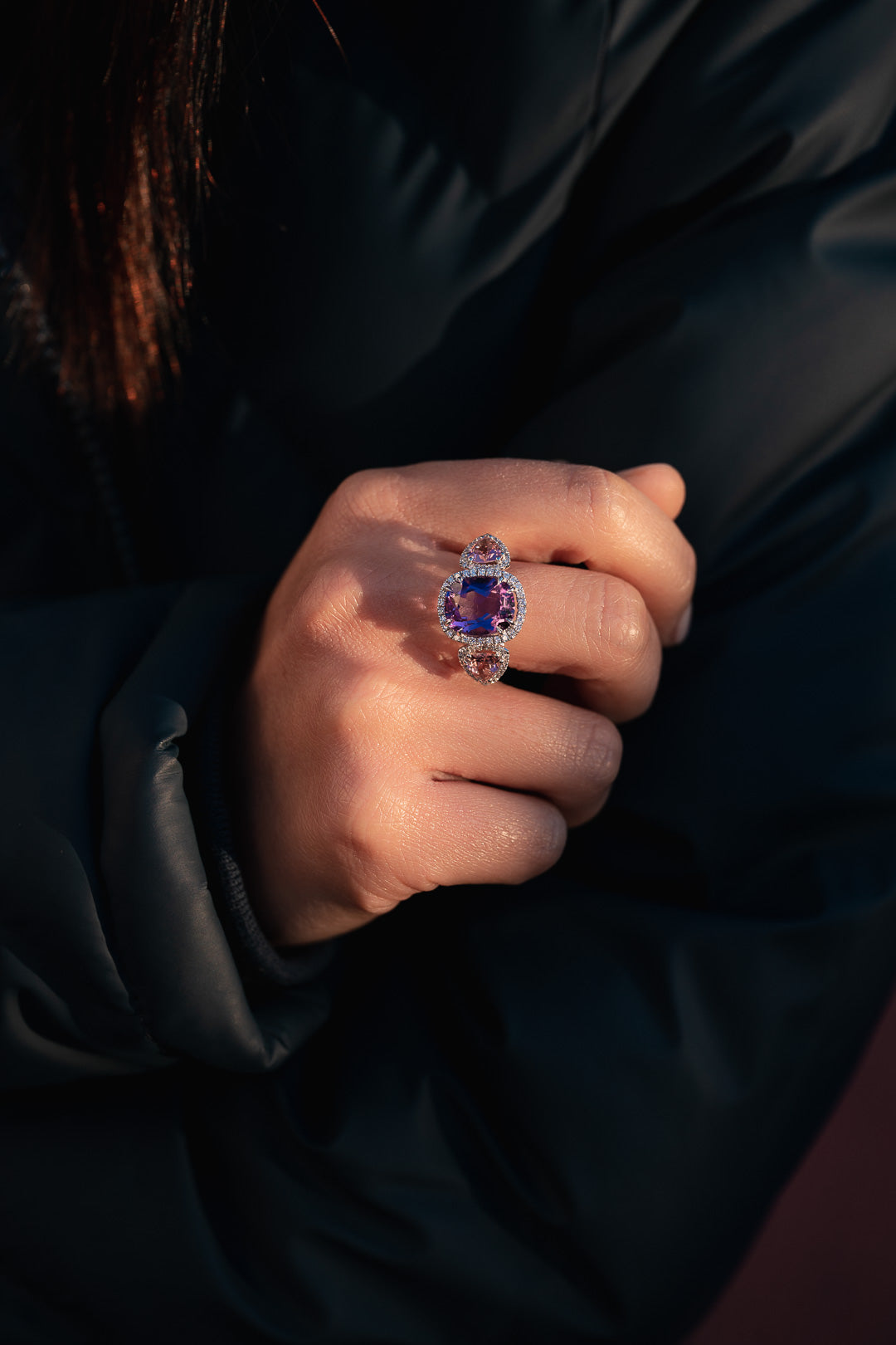 Close-up of a hand wearing a ring with a blue gemstone against a dark background