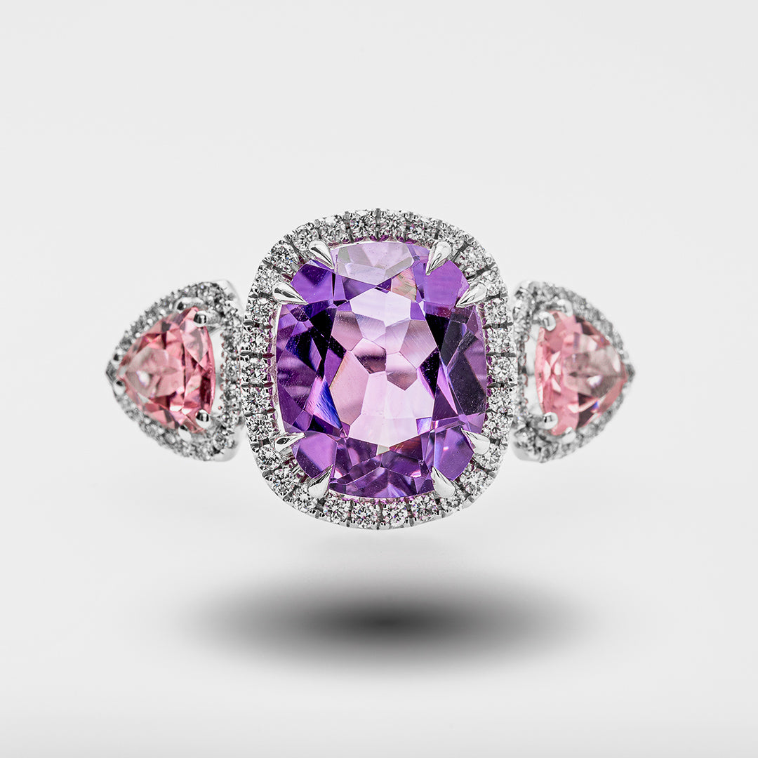 Ring with purple gemstone and pink stones on a light gray background