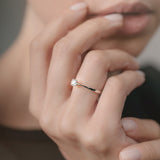 Close-up of a hand wearing a diamond ring with a blurred background