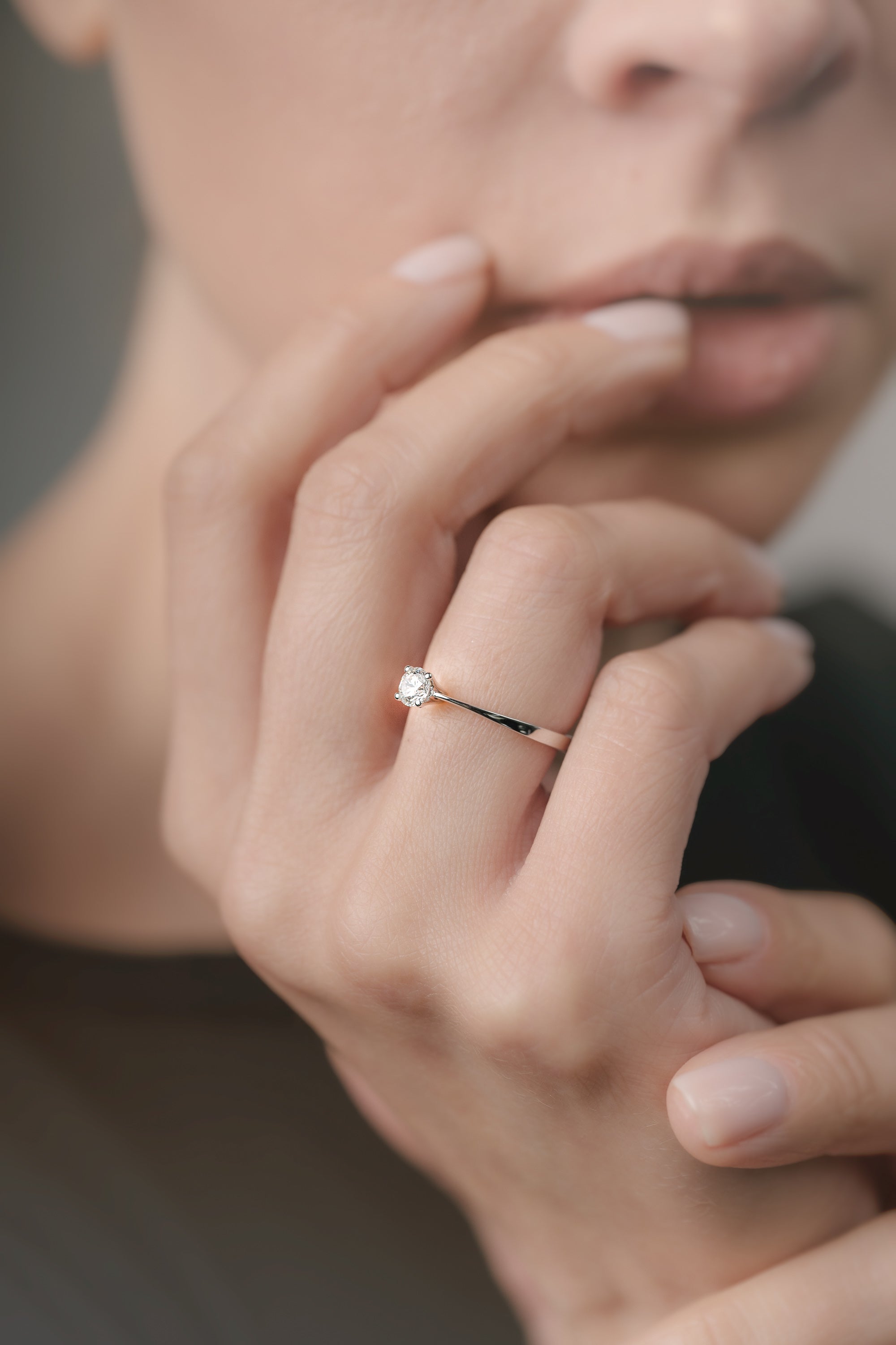 Close-up of a hand wearing a diamond ring with a blurred background