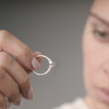 Person holding an engagement ring against a neutral background