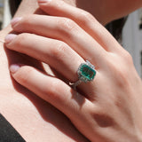 Close-up of a hand wearing an emerald ring with a blurred background
