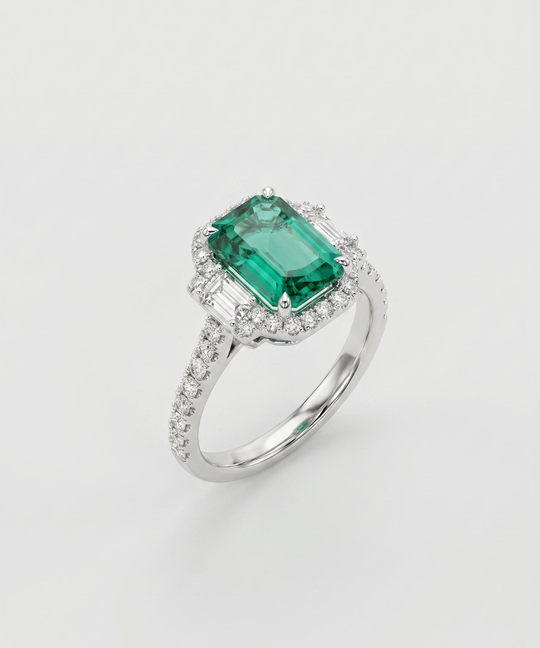 Ring with a green emerald gemstone and diamond-studded band on a light gray background